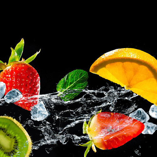 Dragon fruit, lime, orange, strawberries, kiwi and banana with mint leaves and ice splashing through water on a black background.