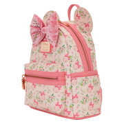 Angled view of the Loungefly Disney Minnie Mouse floral mini backpack showing the floral print, pink trim, velvet bow and gold zip.