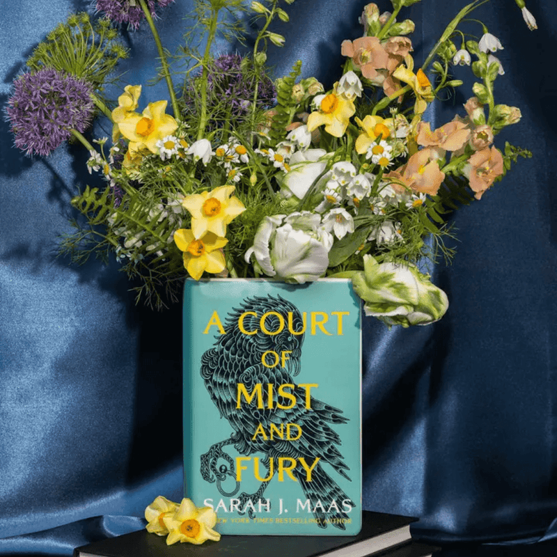 A Court of Mist and Fury book flower vase filled with flowers on a stack of books