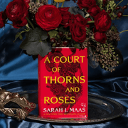 A Court of Thorns and Roses large book vase filled with red flowers