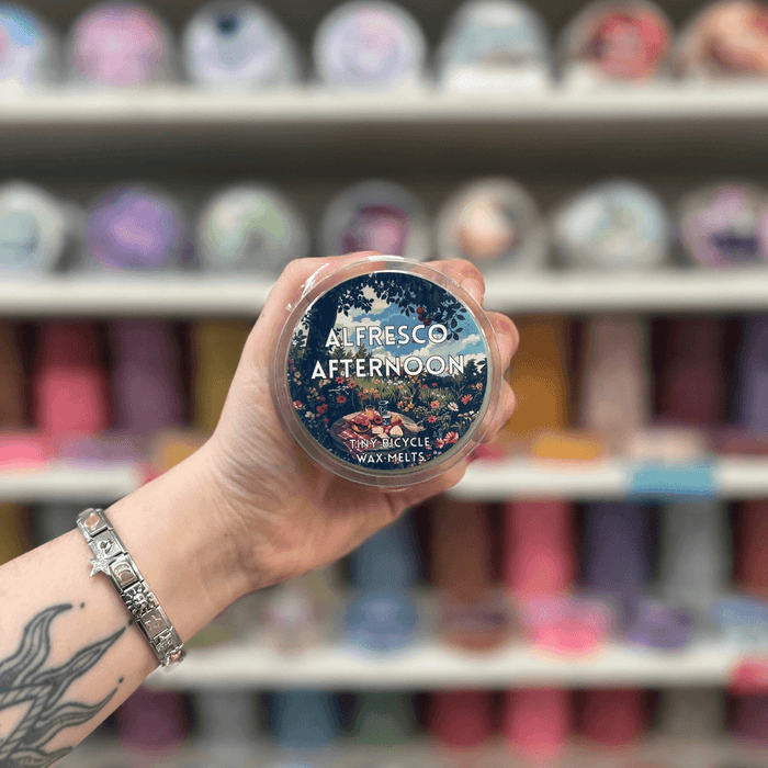 Alfresco Afternoon wax melt pot held in hand with colourful wax melt display in the background
