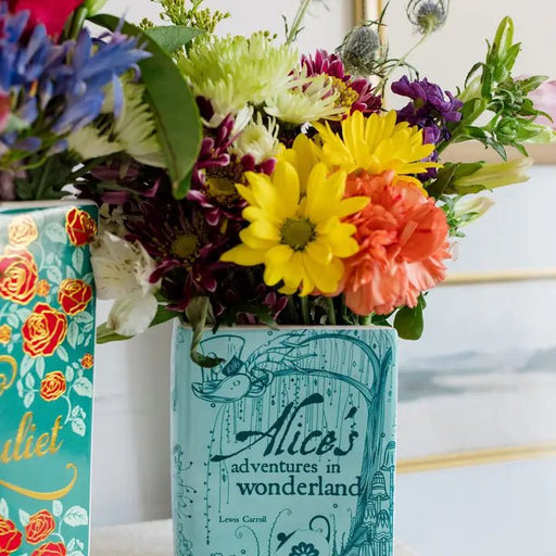 Close-up of turquoise book vase with yellow and purple blooms