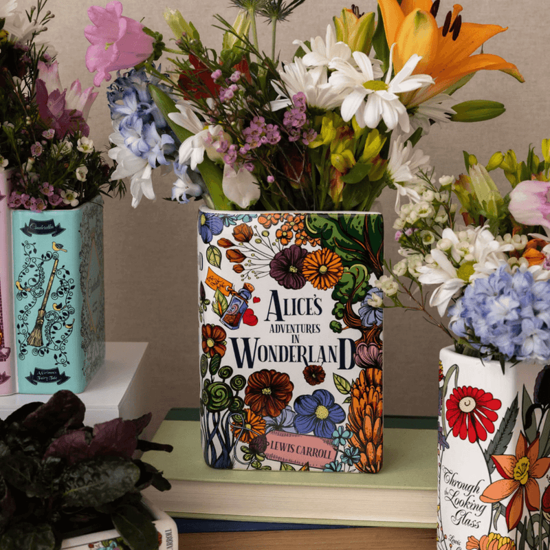 Flatlay of Alice’s Adventures in Wonderland book vase surrounded by florals and books