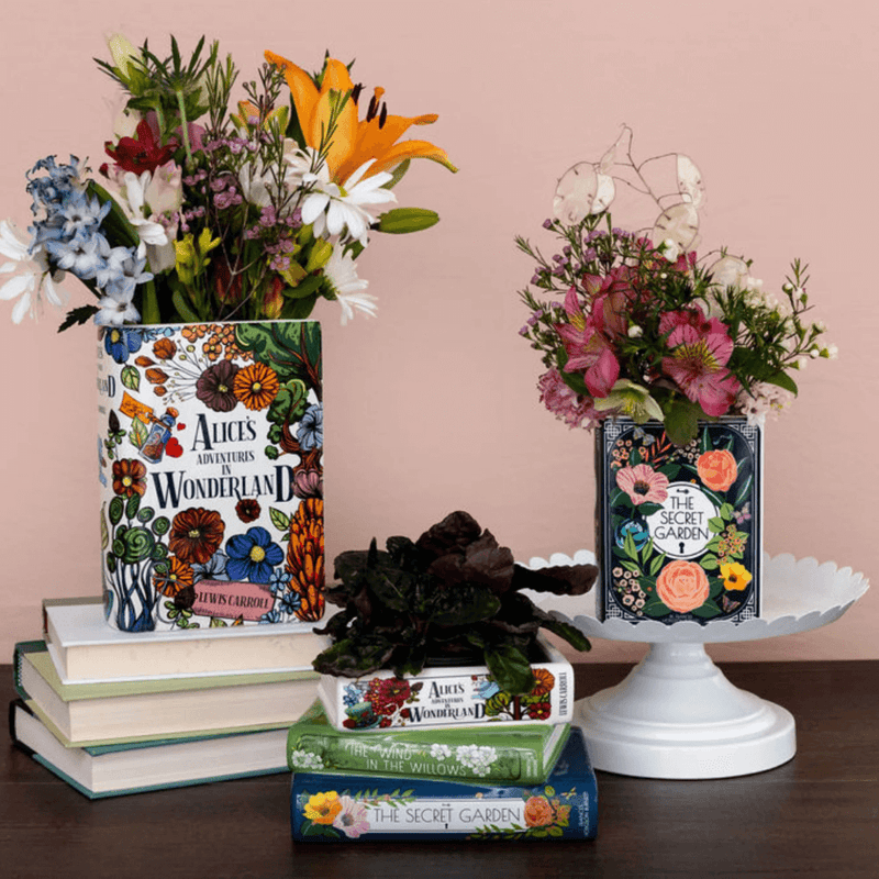 Alice’s Adventures in Wonderland book vase with flowers styled on a white cake stand