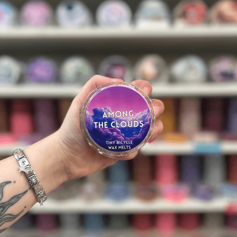 Among the Clouds wax melt pot held in hand with colourful wax melt display in the background