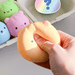 Hand squeezing an orange animal dumpling squishy stress toy