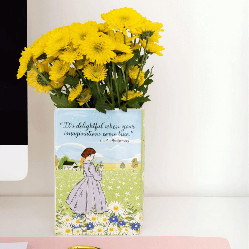 Back of book vase showing Anne holding a book and the quote “It’s delightful when your imaginations come true”

