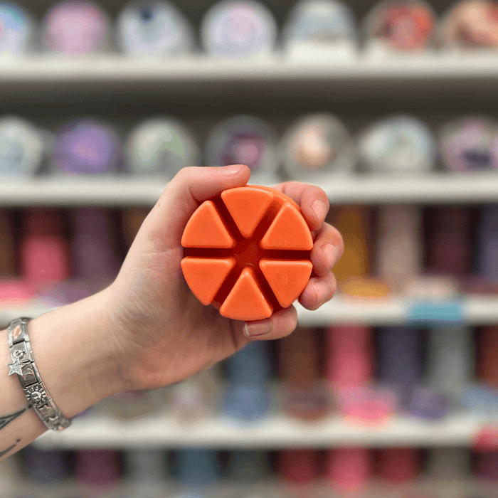 Apple and Cinnamon wax melt segments held in hand with colourful wax melt display in the background