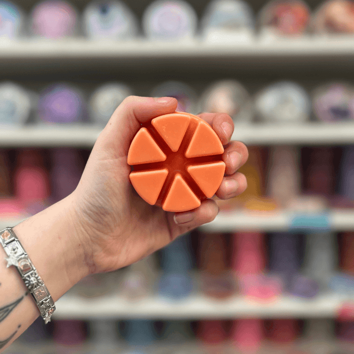 Arabian Princess wax melt segments held in hand with colourful wax melt display in the background
