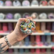 Avocado Fizz wax melt pot held in hand with colourful wax melt display in the background
