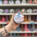 Baby Powder wax melt pot held in hand with colourful wax melt display in the background