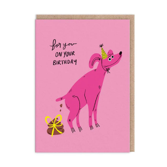 Funny pink birthday card – party dog dropping a ribbon-tied gift; text reads For you on your birthday – A6 with kraft envelope