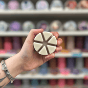 Bakehouse Biscuit wax melt segments held in hand with colourful wax melt display in the background