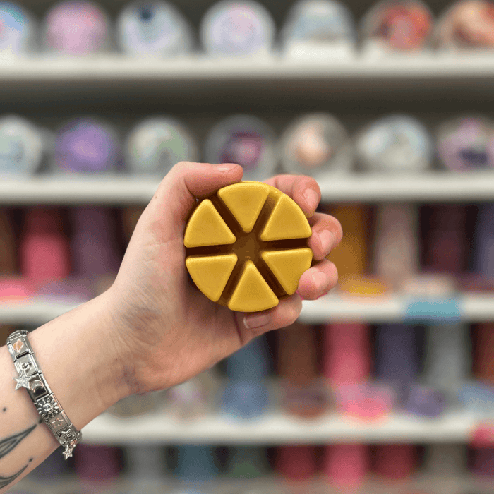 Banana Walnut Loaf wax melt segments held in hand with colourful wax melt display in the background