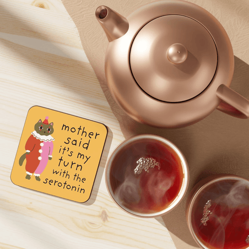 Betiobca My Turn with the Serotonin Cat coaster shown on a table beside tea cups and a teapot
