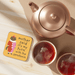 Betiobca My Turn with the Serotonin Cat coaster shown on a table beside tea cups and a teapot