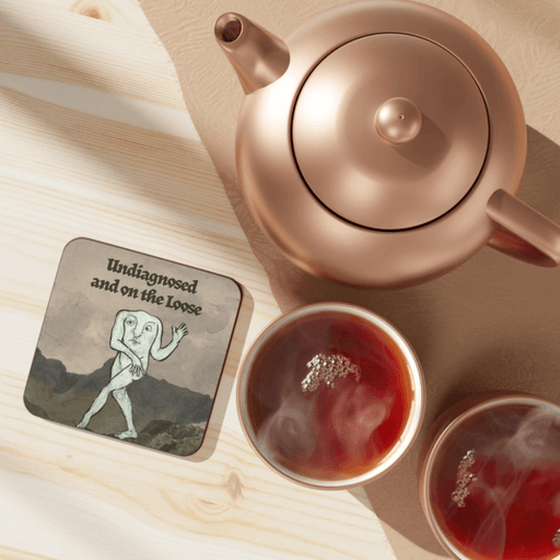 Undiagnosed and On the Loose Betiobca coaster beside a teapot and cups of tea