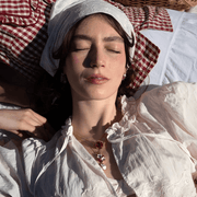 Model wearing Bill Skinner Strawberry and Hanging Mouse Pendant with a second strawberry necklace and white ruffled blouse