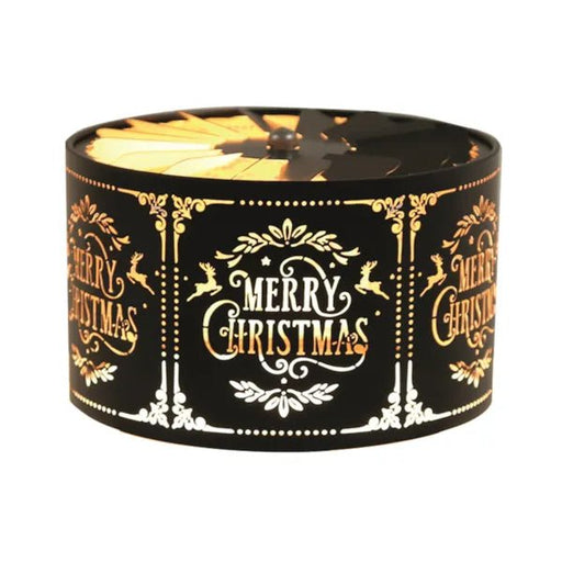 Black and gold carousel candle shade with 'Merry Christmas' text and reindeer silhouette, glowing above a jar candle.

