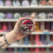 Blood Moon Ball wax melt pot held in hand with colourful wax melt display in the background