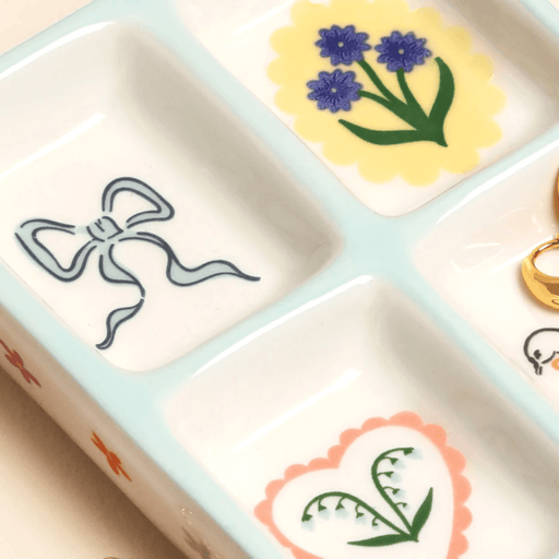 Detail of blue bow and floral ceramic trinket tray with illustrated compartments