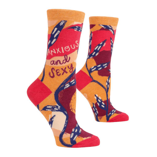 Angled view of Blue Q crew socks showing Anxious and Sexy text with warm orange-red palette and graphic vines