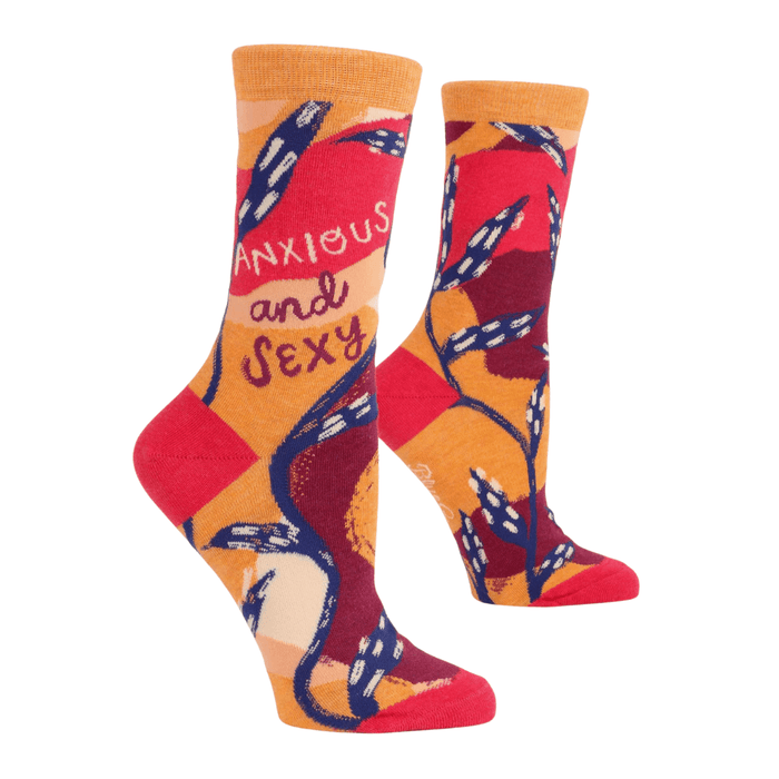 Angled view of Blue Q crew socks showing Anxious and Sexy text with warm orange-red palette and graphic vines