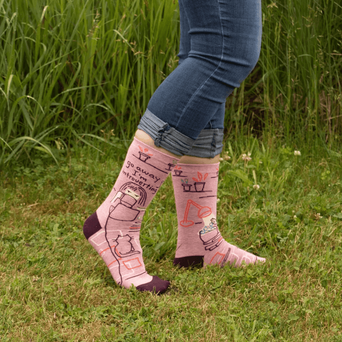 Person wearing Blue Q women’s crew socks reading “Go Away I’m Introverting” in pink and burgundy