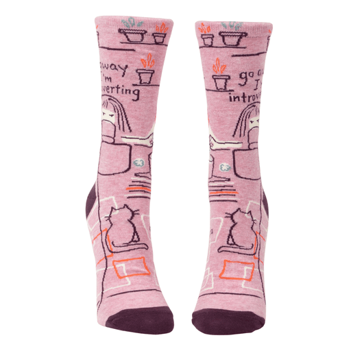 Front view of Blue Q women’s crew socks in pink with plum cuffs and toes, desk-and-cat illustration and the slogan go away I’m introverting