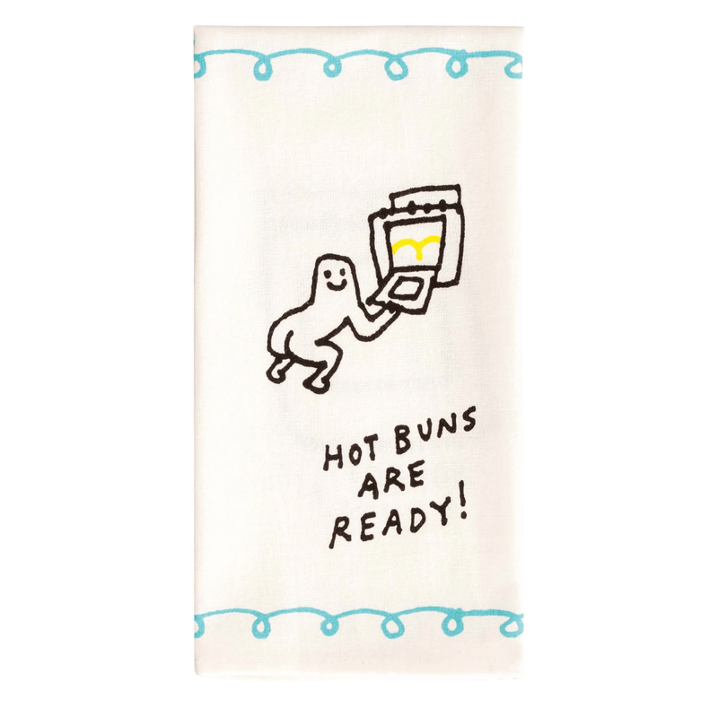 Front of Blue Q Hot Buns Are Ready tea towel with retro character holding tray of buns