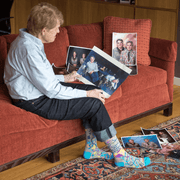 Person on a red sofa wearing Blue Q women’s crew socks reading “I Love My Asshole Kids”