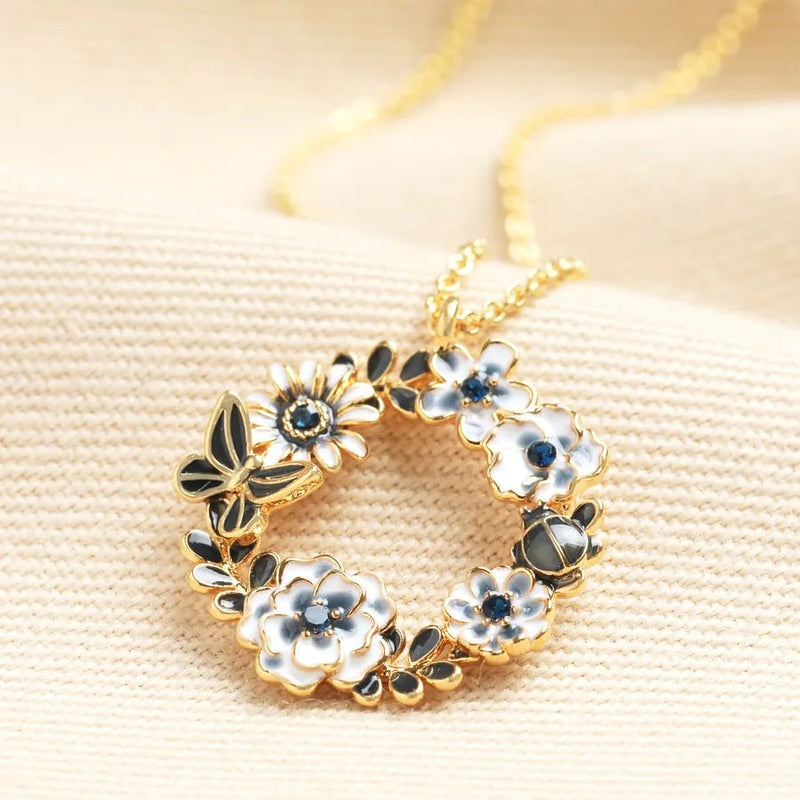 Gold butterfly and flower circle pendant necklace with blue and white enamel on a gold chain