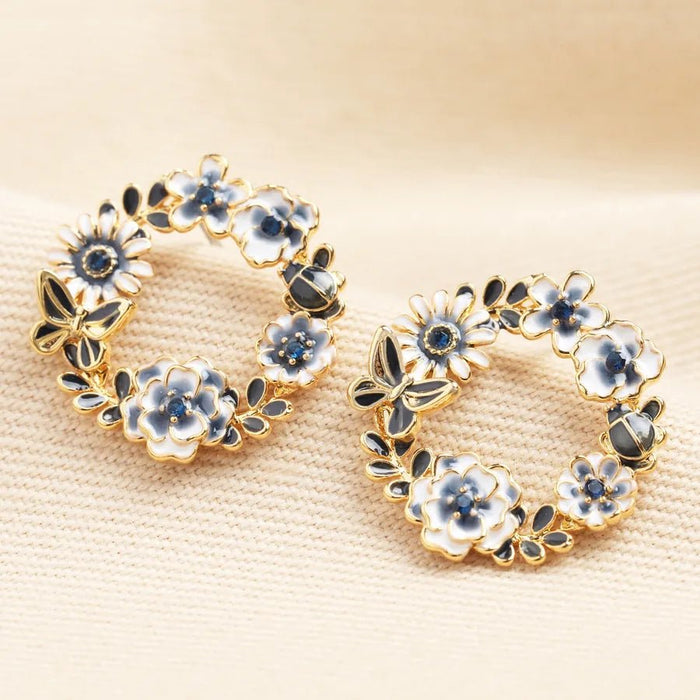 Gold butterfly and flower circle stud earrings with blue and white enamel floral details