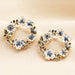 Gold butterfly and flower circle stud earrings with blue and white enamel floral details