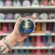 Bluebell wax melt pot held in hand with colourful wax melt display in the background