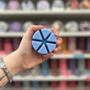 Bluebell wax melt segments held in hand with colourful wax melt display in the background