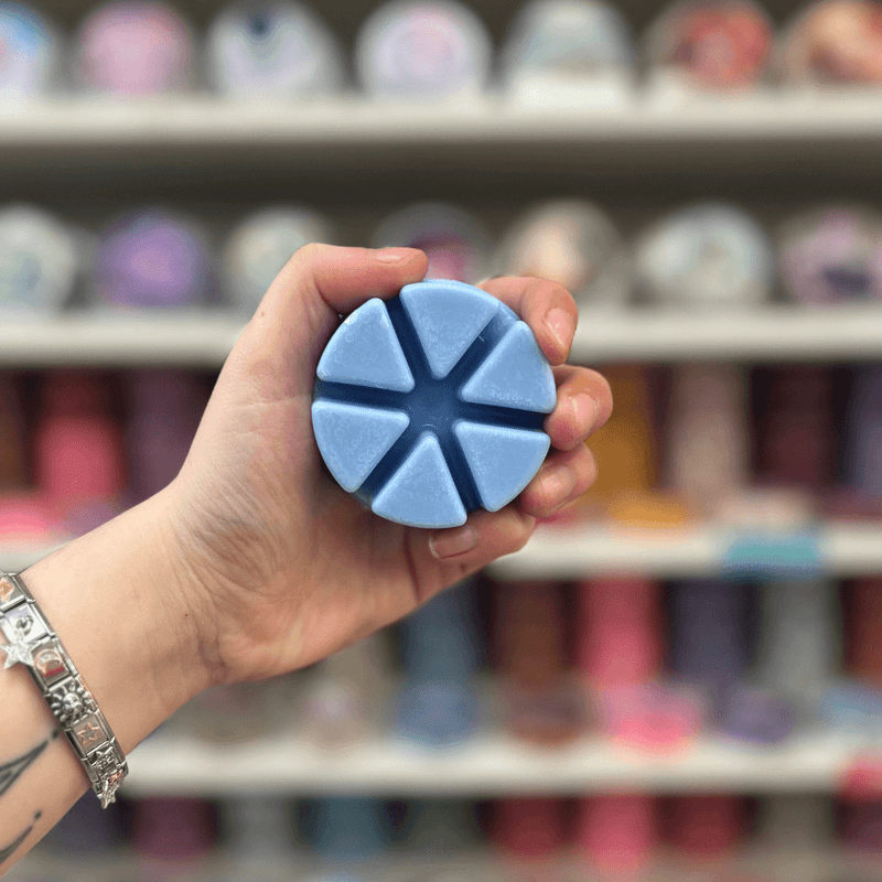 Bluebell wax melt segments held in hand with colourful wax melt display in the background