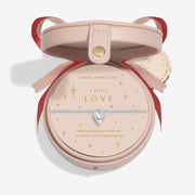 “Blush‑pink round bauble gift box holding ‘A Little Love’ bracelet”
