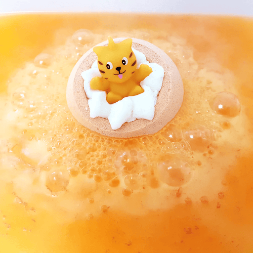Bomb Cosmetics Meow For Now Bath Blaster fizzing in the bath with a cute cat topper and orange water