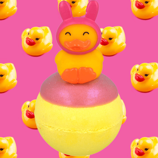 Bomb Cosmetics Snuggle Duck Bath Blaster with bunny hat duck topper on a pink background with rubber ducks