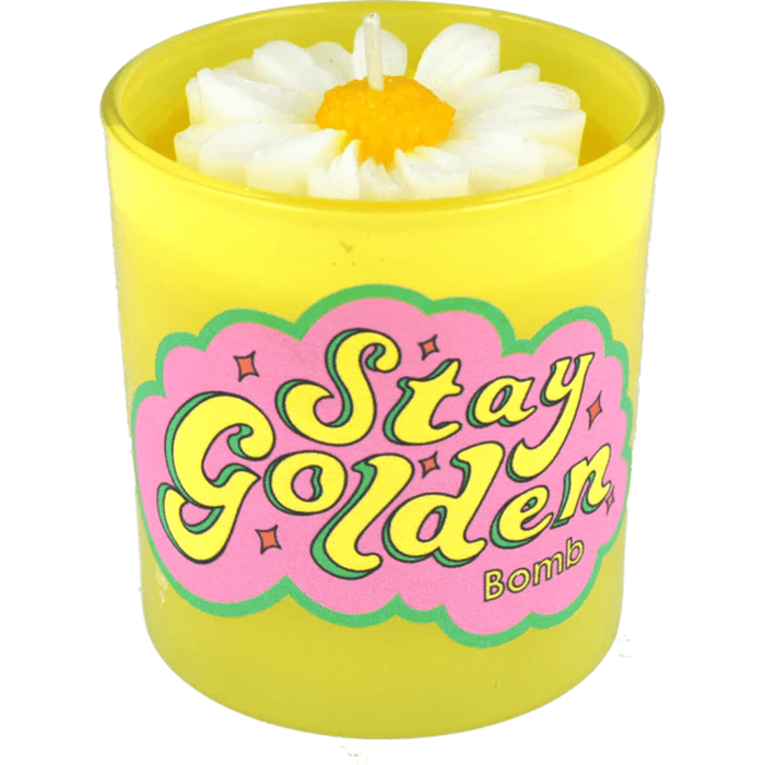 Bomb Cosmetics Stay Golden flower candle—yellow jar with white wax daisy bloom, papaya-mango-guava tropical scent.