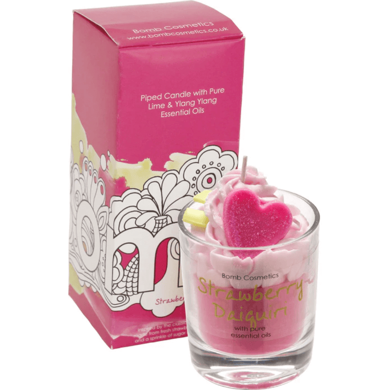 Bomb Cosmetics Strawberry Daiquiri piped scented candle—pink wax swirl with heart topper beside matching cocktail-pink gift box.