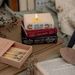 Jane Austen book stack shaped candle lit on a book with matches and dried flowers

