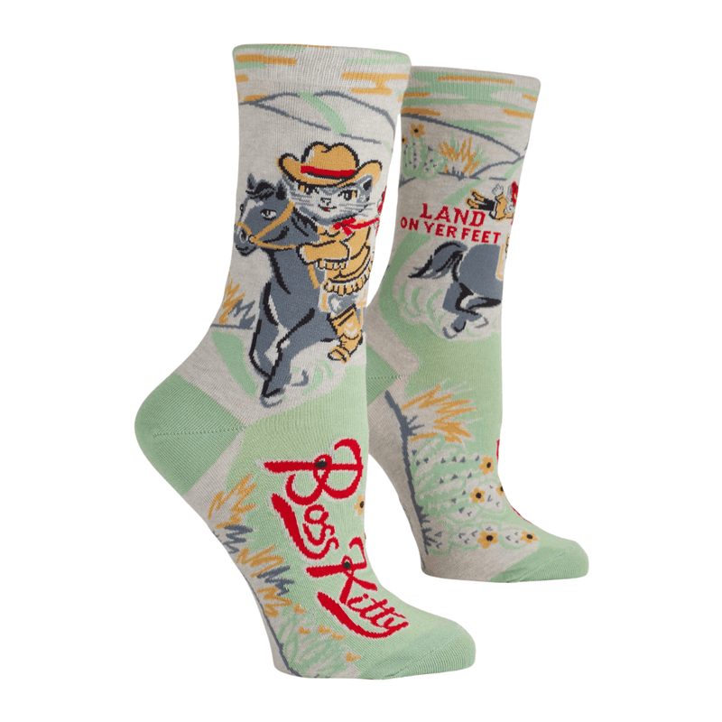 Mint green crew socks featuring a cowboy cat riding a horse with the phrase “Land on yer feet.”