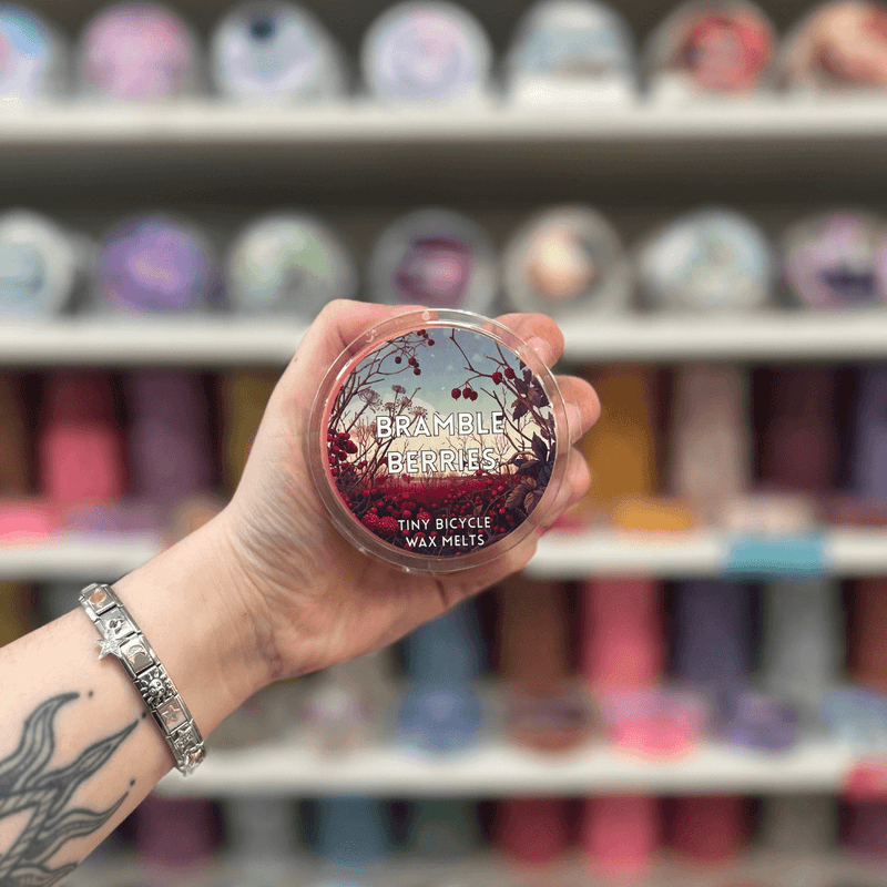 Bramble Berries wax melt pot held in hand with colourful wax melt display in the background