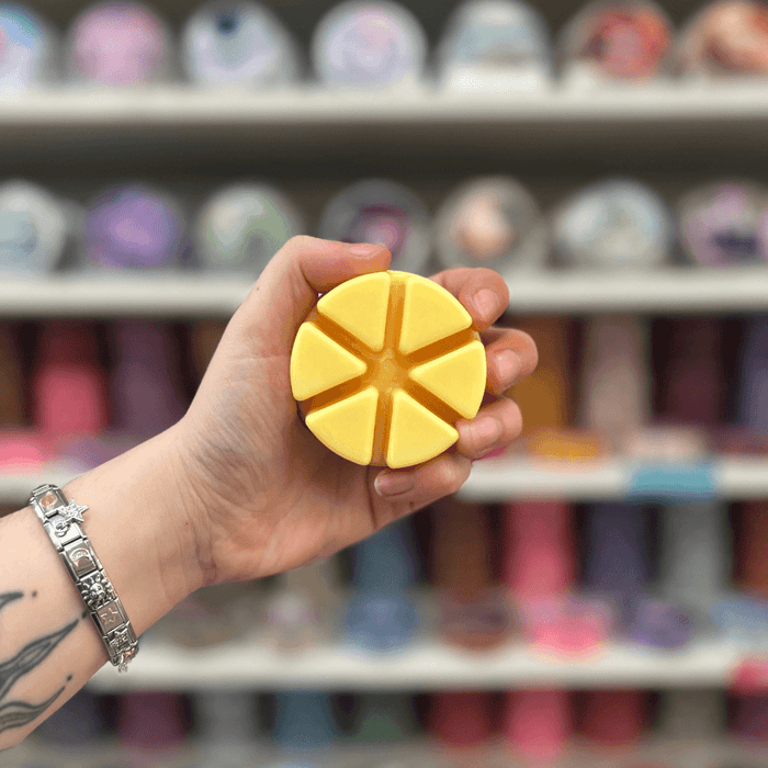 Brazilian Summer wax melt segments held in hand with colourful wax melt display in the background