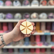 Cream segmented wax melt held in hand in front of a colourful wax melt display