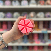 Bubblegum wax melt segments held in hand with colourful wax melt display in the background