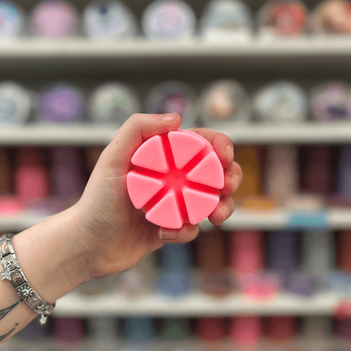 Bubblegum wax melt segments held in hand with colourful wax melt display in the background