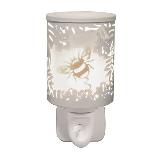 White plug in wax melt burner glowing with a bumblebee motif and floral cut-out detailing, with an on/off switch on the plug base.